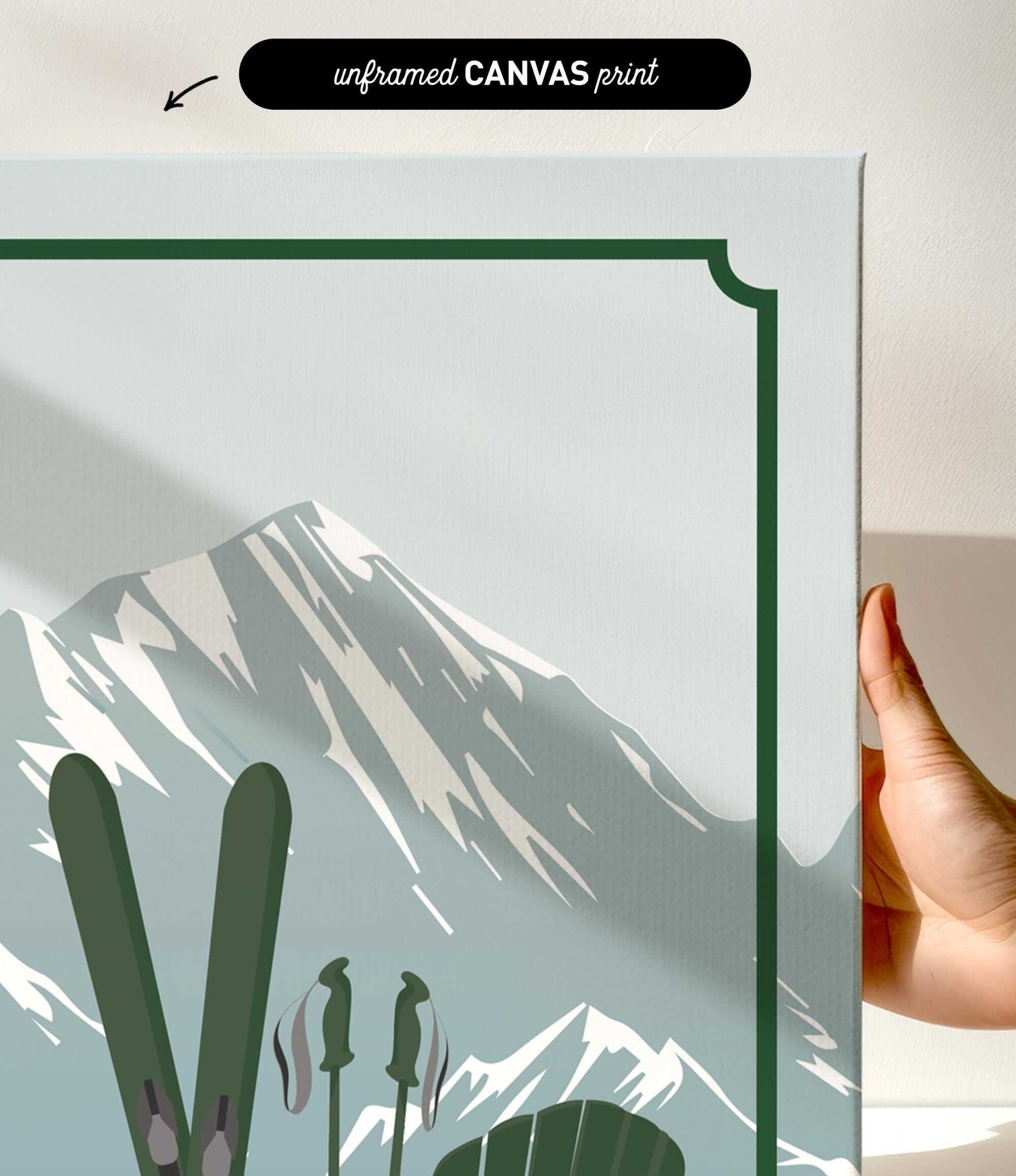 a hand holding a framed print of a mountain landscape with skis and ski poles.