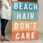 a woman standing next to a sign that says beach hair don't care