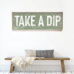 a wooden sign that says take a dip on a bench