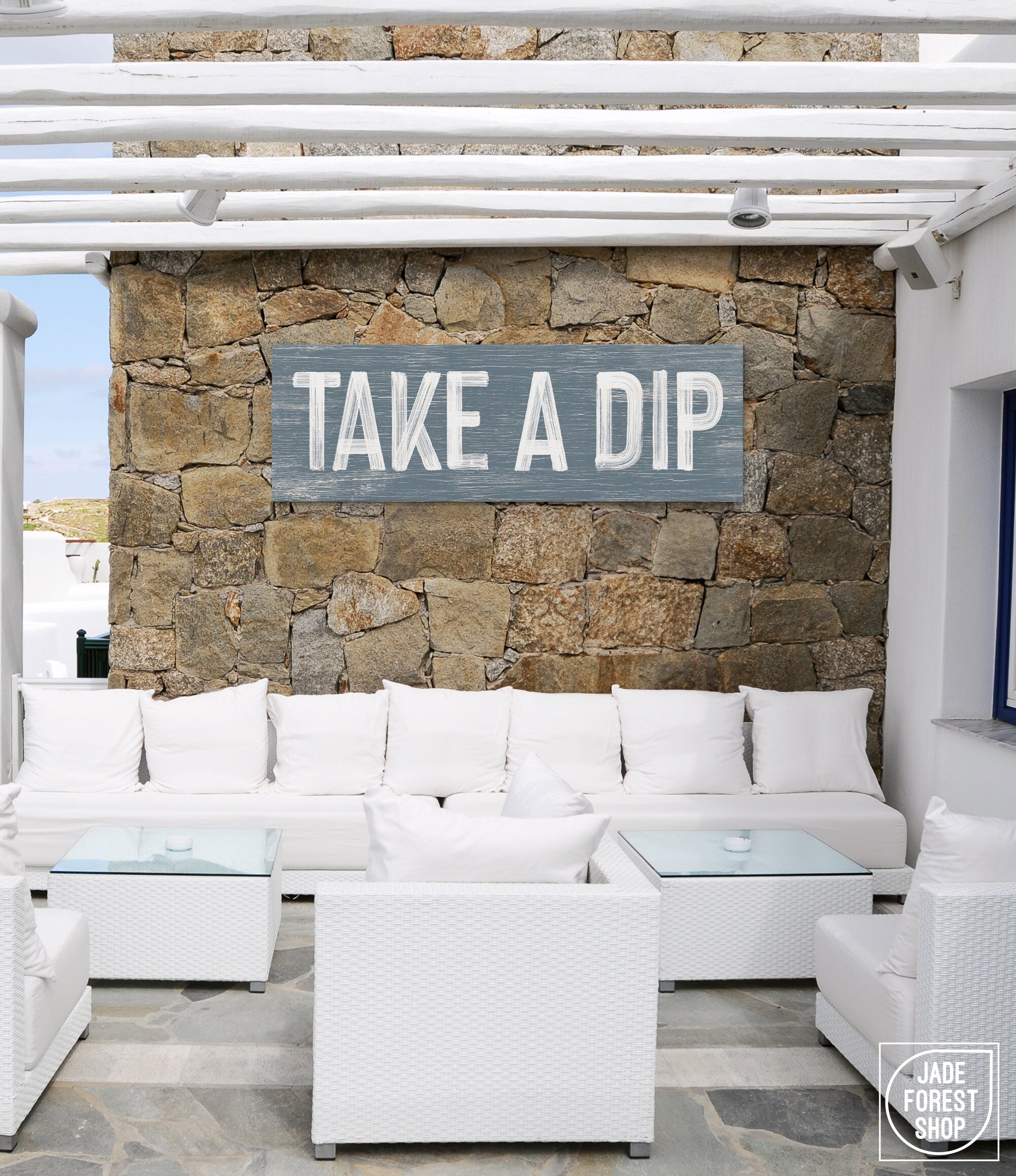 a white couch sitting under a wooden sign on a stone wall