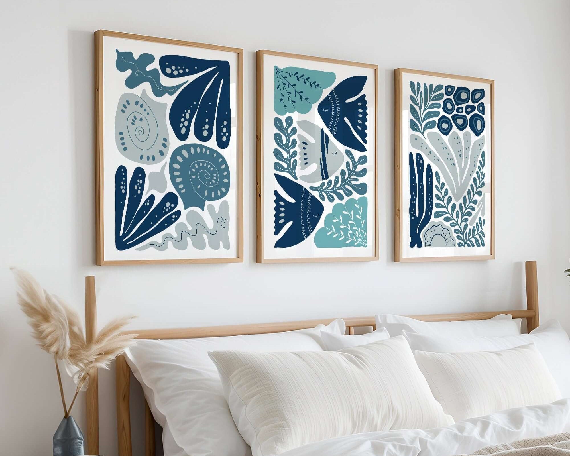 A cozy bedroom with a wooden bed, white bedding, and the Ocean Blocks Triptych (Set of Three Prints | 303) above the headboard—perfect for elevating your home decor.