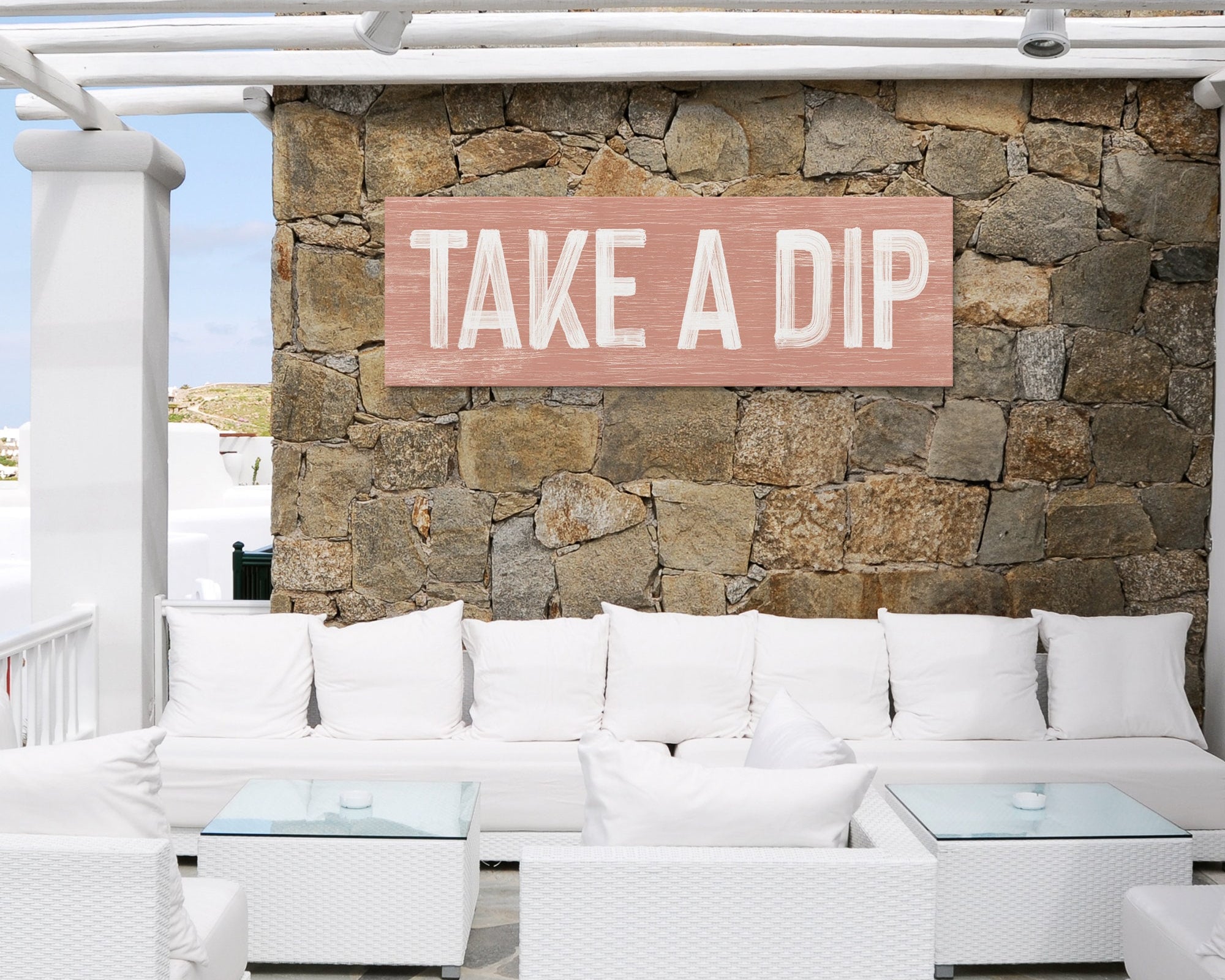 a white couch sitting under a wooden sign on a stone wall