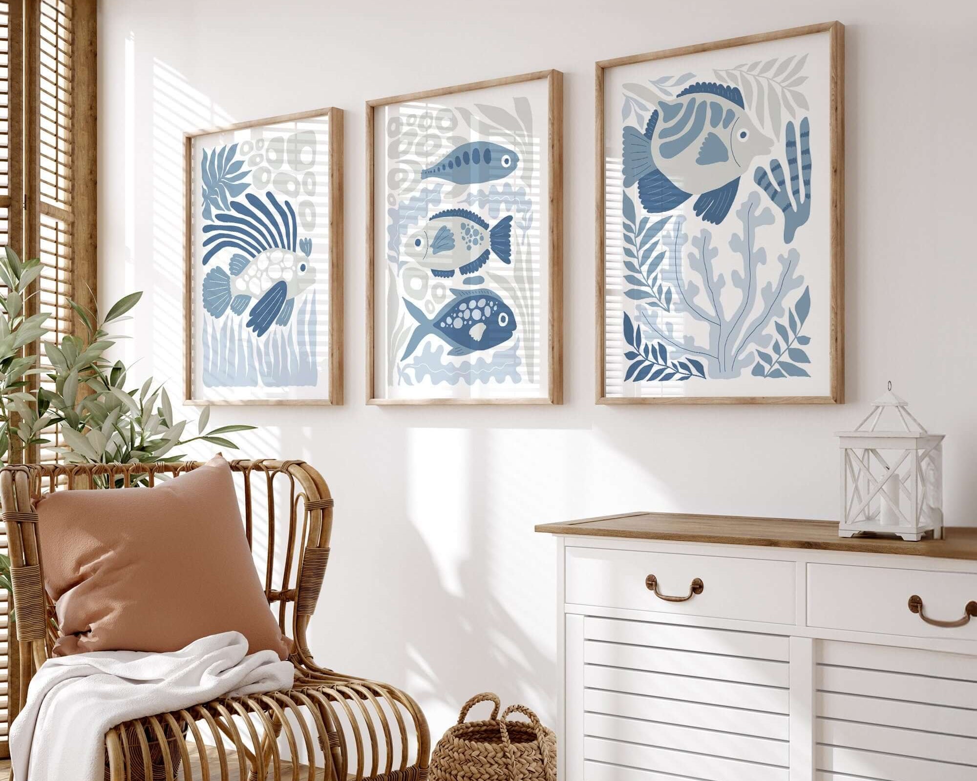 A cozy room with a rattan chair, white sideboard, and the Ocean Blocks Triptych (Set of Three Prints | 341)—a striking blue fish wall art set perfect for elevating your home decor.