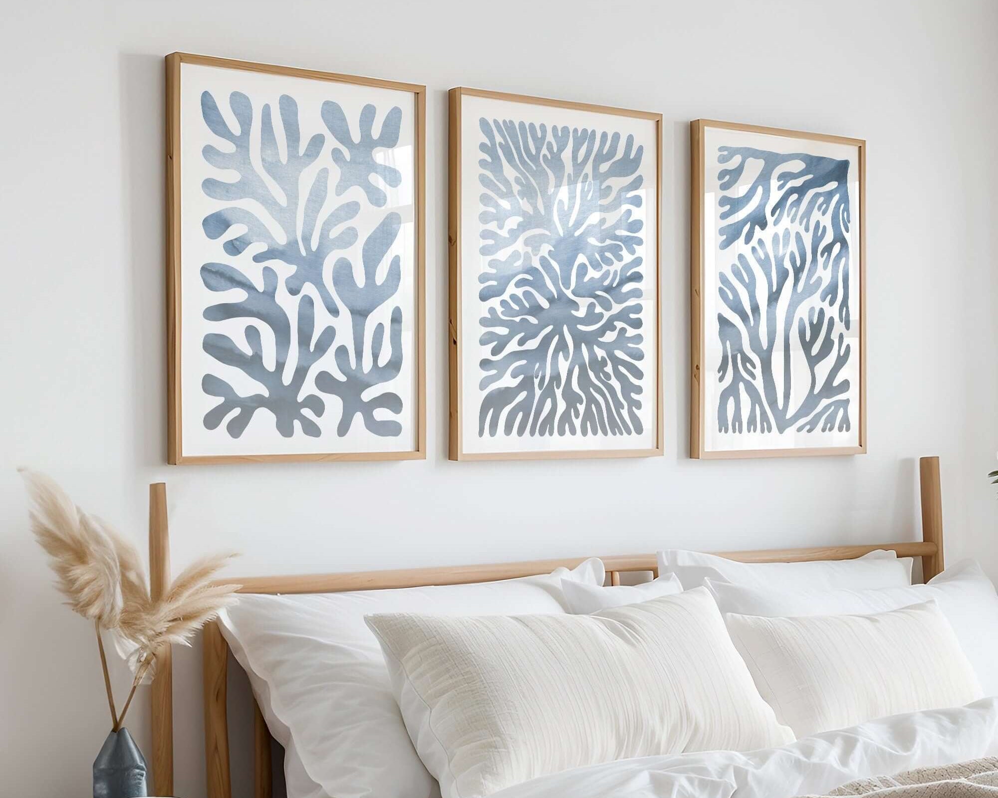 Minimalist bedroom with a wooden bed, neutral bedding, and the Ocean Blocks Triptych | Set of Three Prints | 323—a striking abstract blue wall art collection displayed above the headboard.