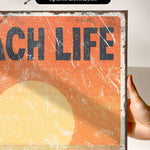 a person holding up a sign that says teach life