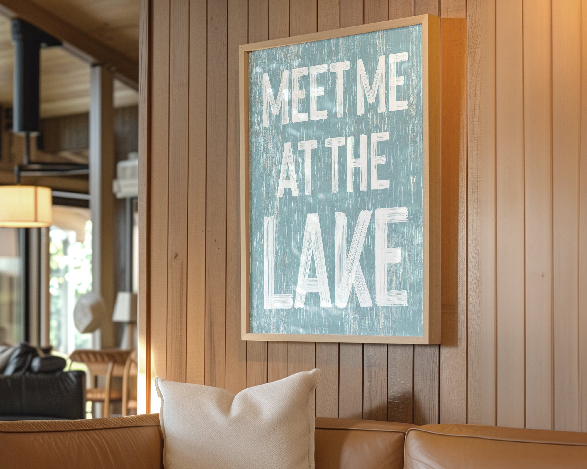 The Meet Me at the Lake Sign, Tide is displayed on a wood wall above a tan couch with a white pillow, bringing cozy lake house vibes to this modern farmhouse space.