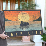 a man holding a sign that says lake life