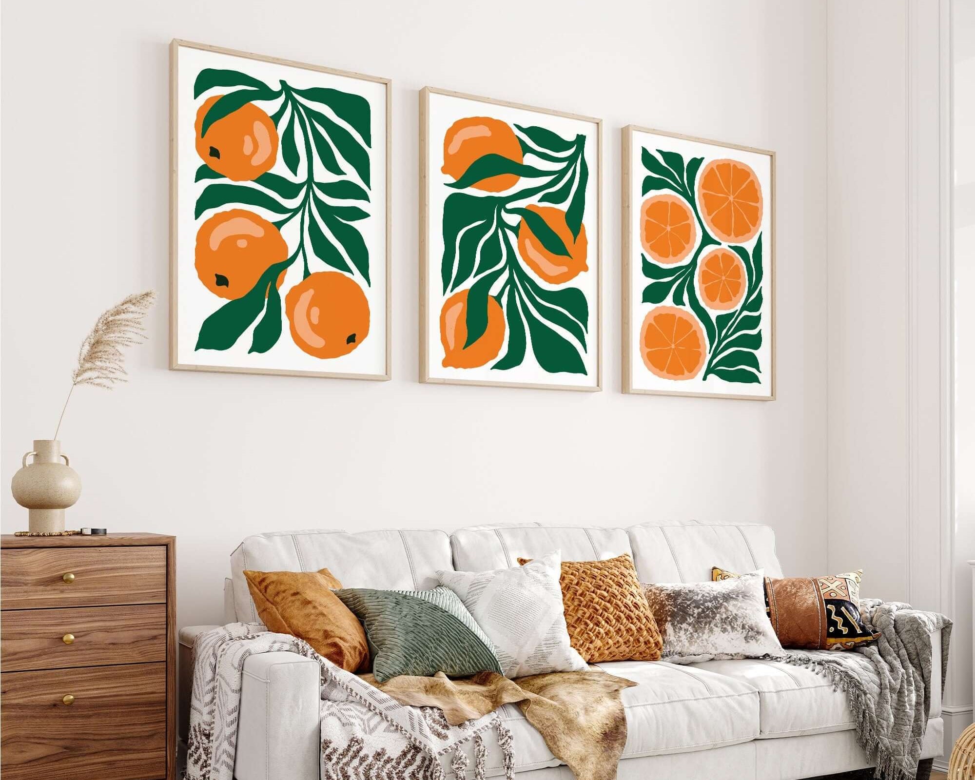 Modern living room with a white sofa and the Tropical Blocks Triptych (Set of Three Prints | 424), featuring vibrant orange and green fruit prints as wall art above.