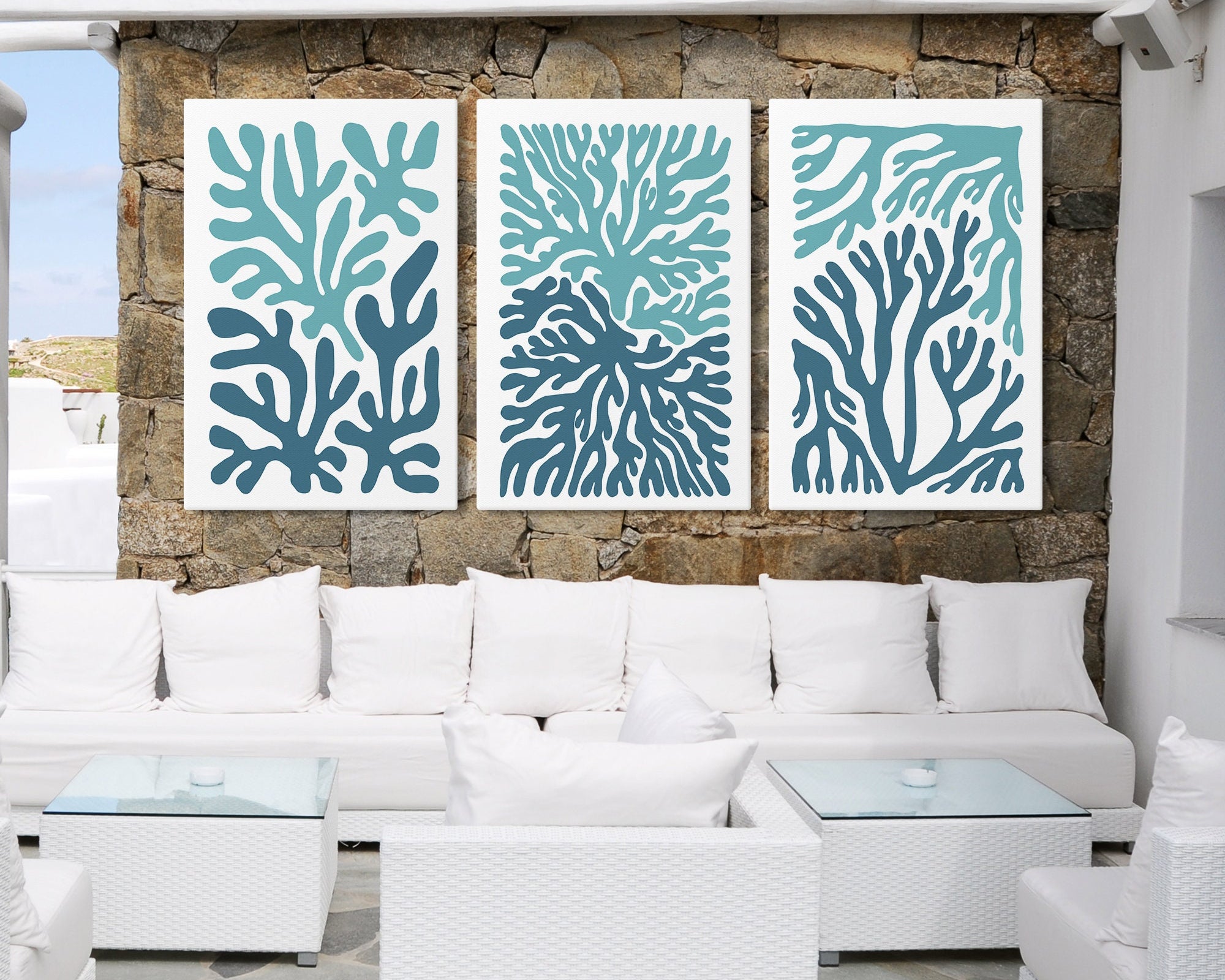 White outdoor seating area featuring the Ocean Blocks Triptych (Set of Three Prints | 308), bold abstract blue botanical wall art that brings modern flair to the stone wall and elevates your home decor.
