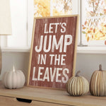 a wooden sign that says let's jump in the leaves