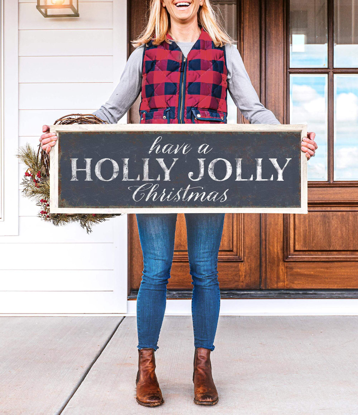 a woman holding a sign that says have a holly jolly christmas