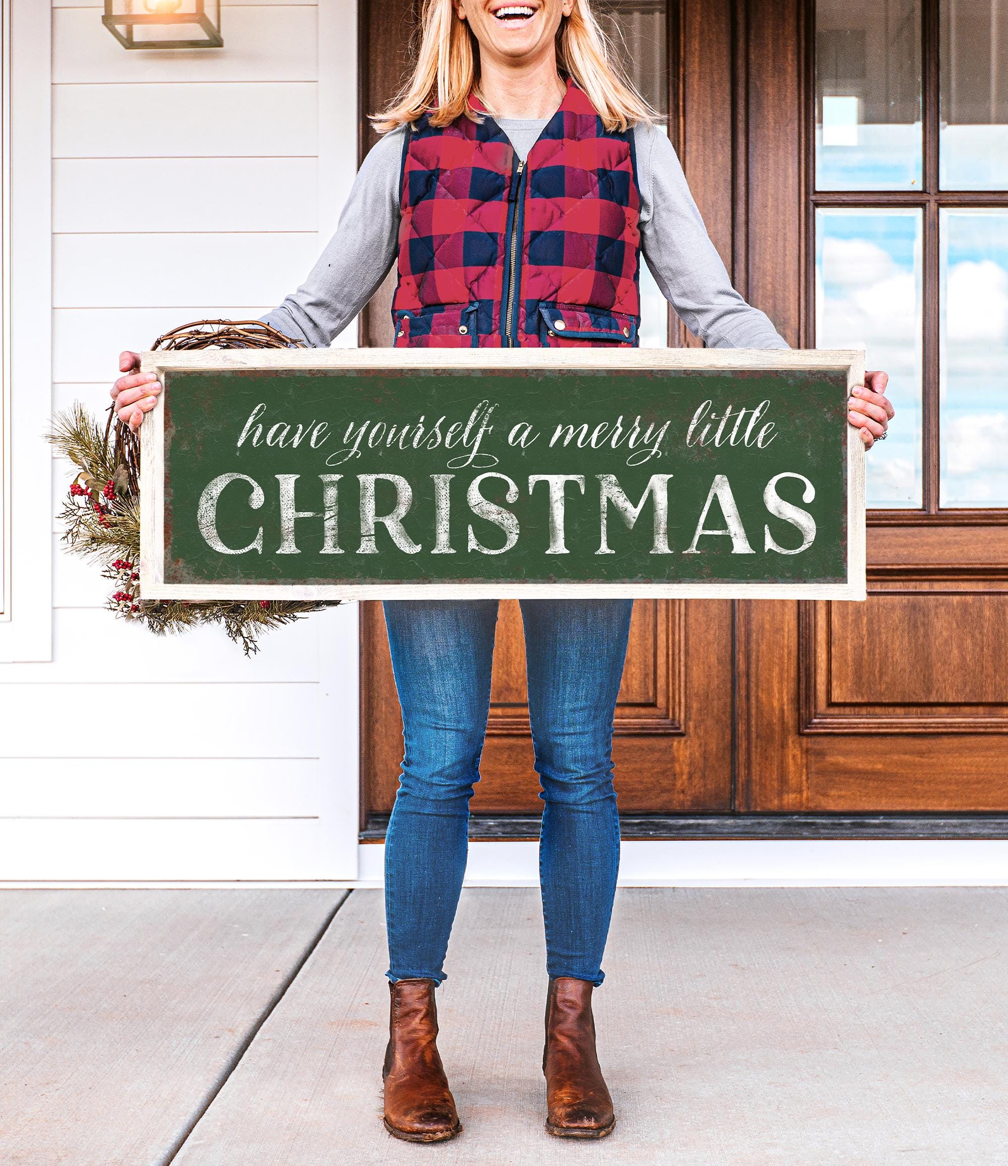 a woman holding a sign that says have yourself a merry little christmas