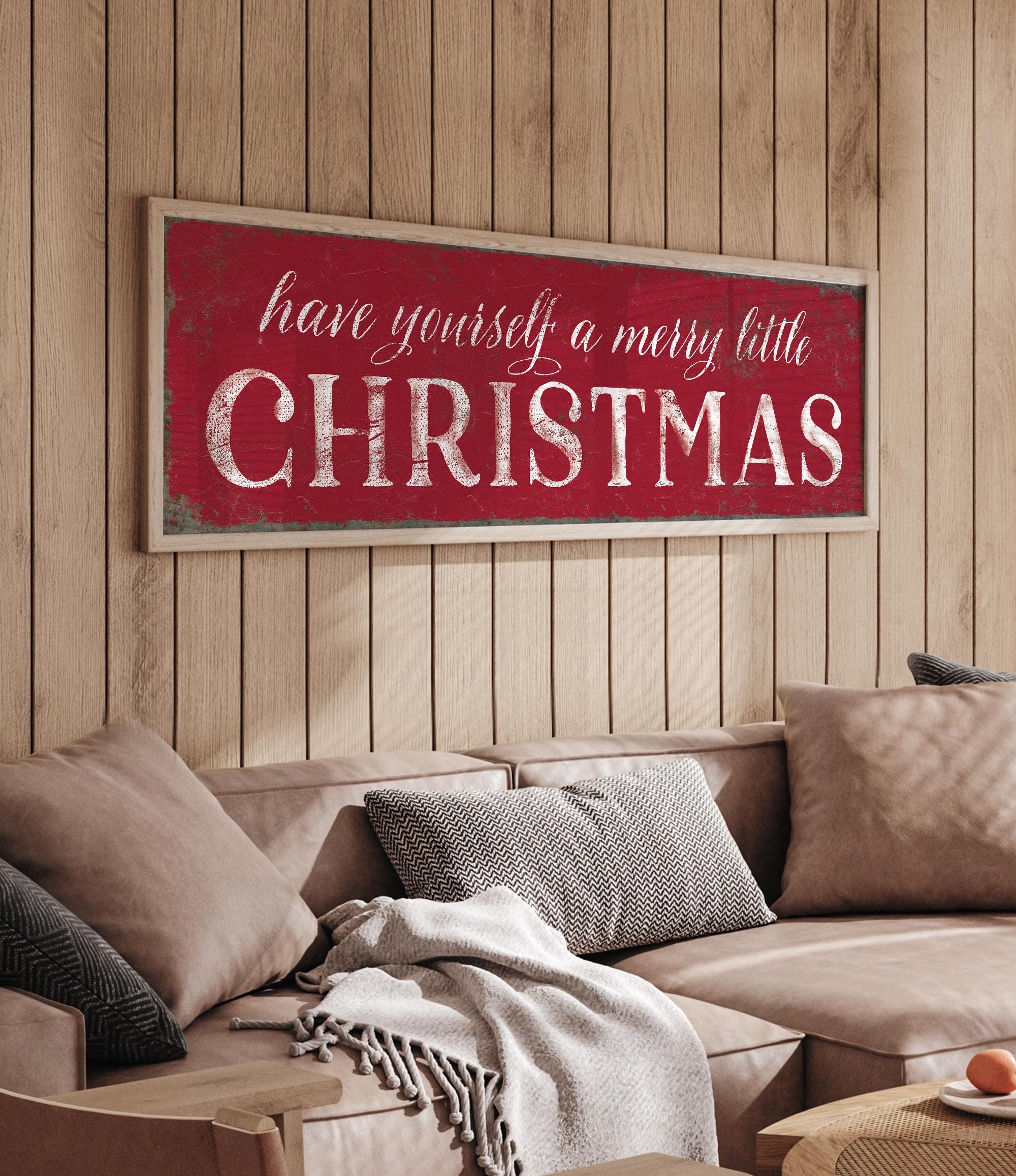 a living room with a couch and a christmas sign on the wall