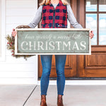 a woman holding a sign that says have yourself a merry little christmas