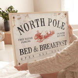 a woman holding a sign that says north pole bed and breakfast