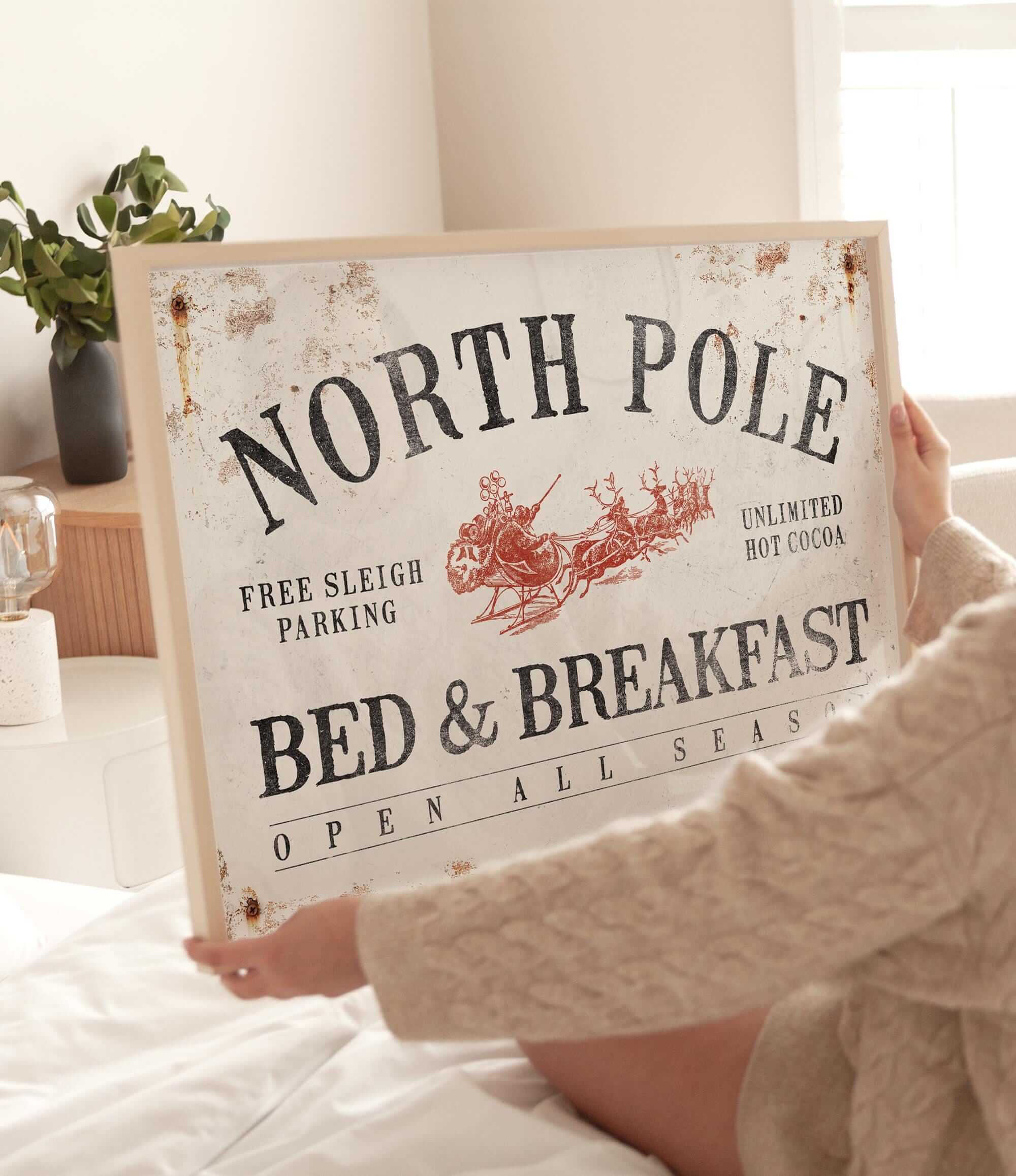 a woman holding a sign that says north pole bed and breakfast