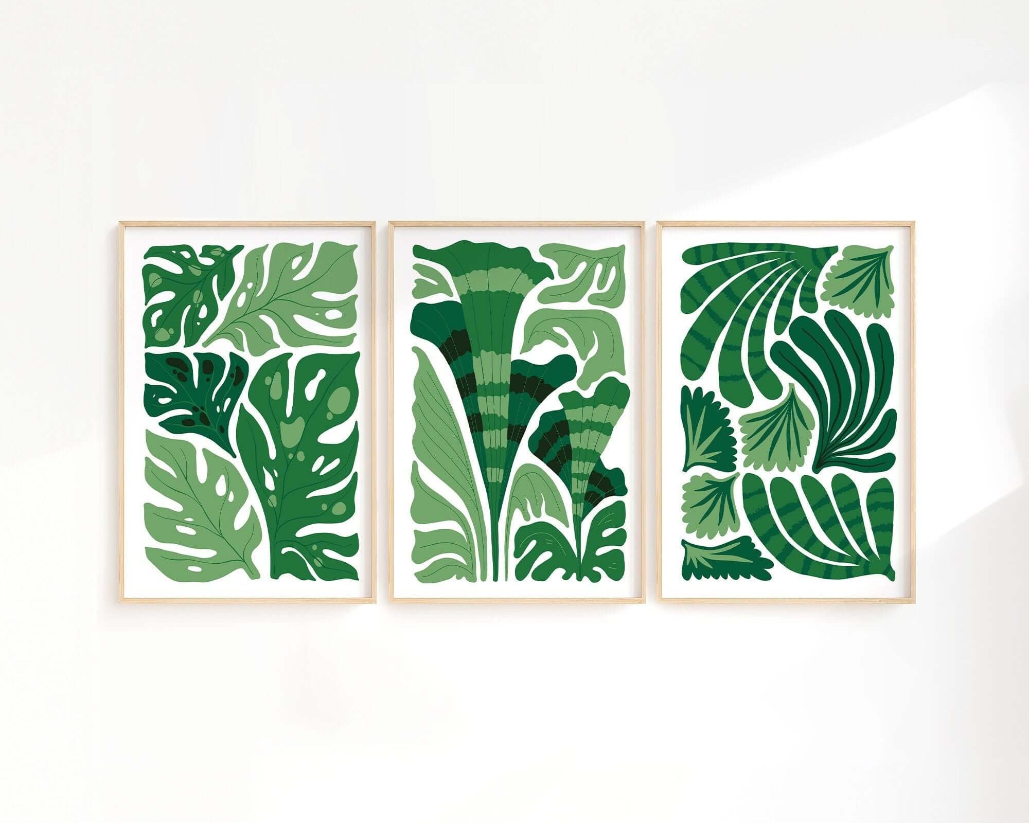 Enhance your space with the Tropical Blocks Triptych (Set of Three Prints | 401)—a trio of framed art prints displaying abstract green leaf designs on a crisp white background.