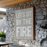 a sign on a stone wall that says let's sit by the fire