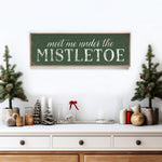 a wooden sign that says meet me under the mistletoe