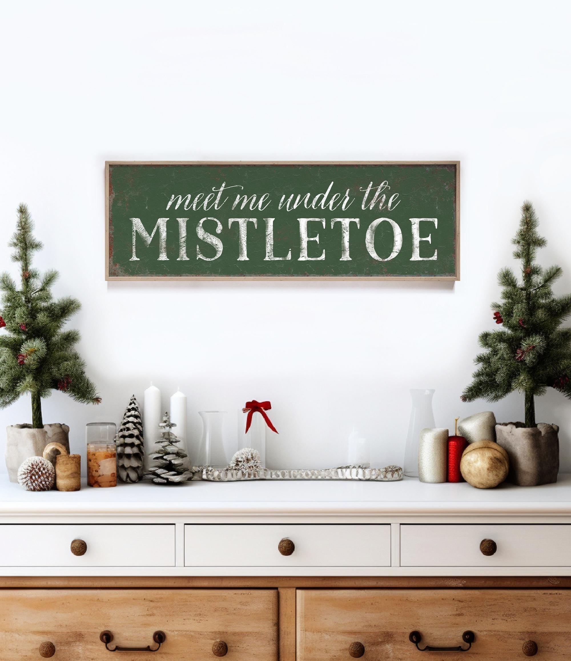 a wooden sign that says meet me under the mistletoe