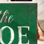 a hand holding a green sign that says the joe