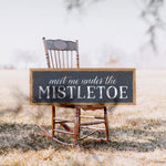 a wooden rocking chair with a sign that says meet me under the mistletoe