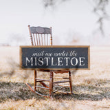 a wooden rocking chair with a sign that says meet me under the mistletoe