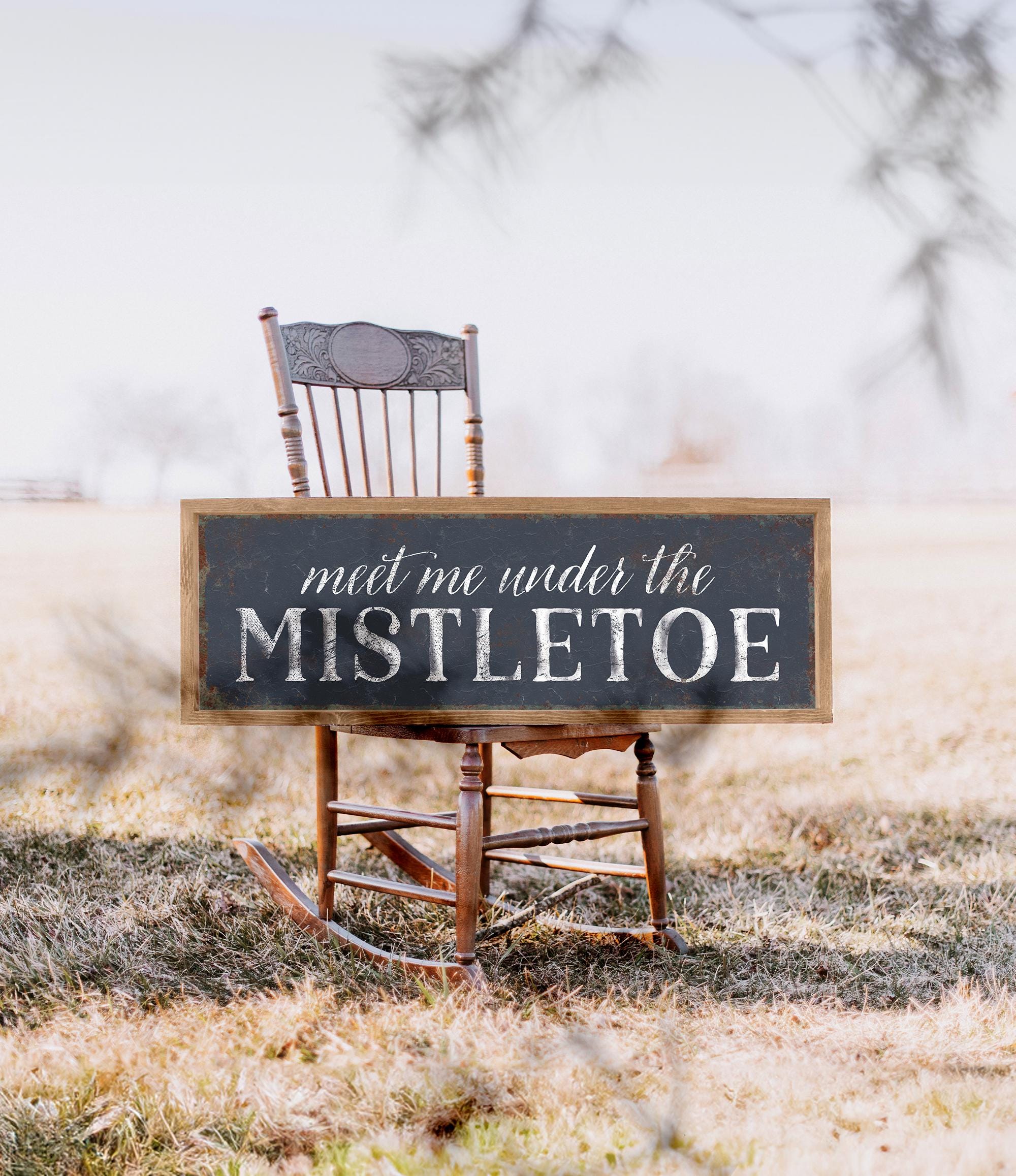 a wooden rocking chair with a sign that says meet me under the mistletoe