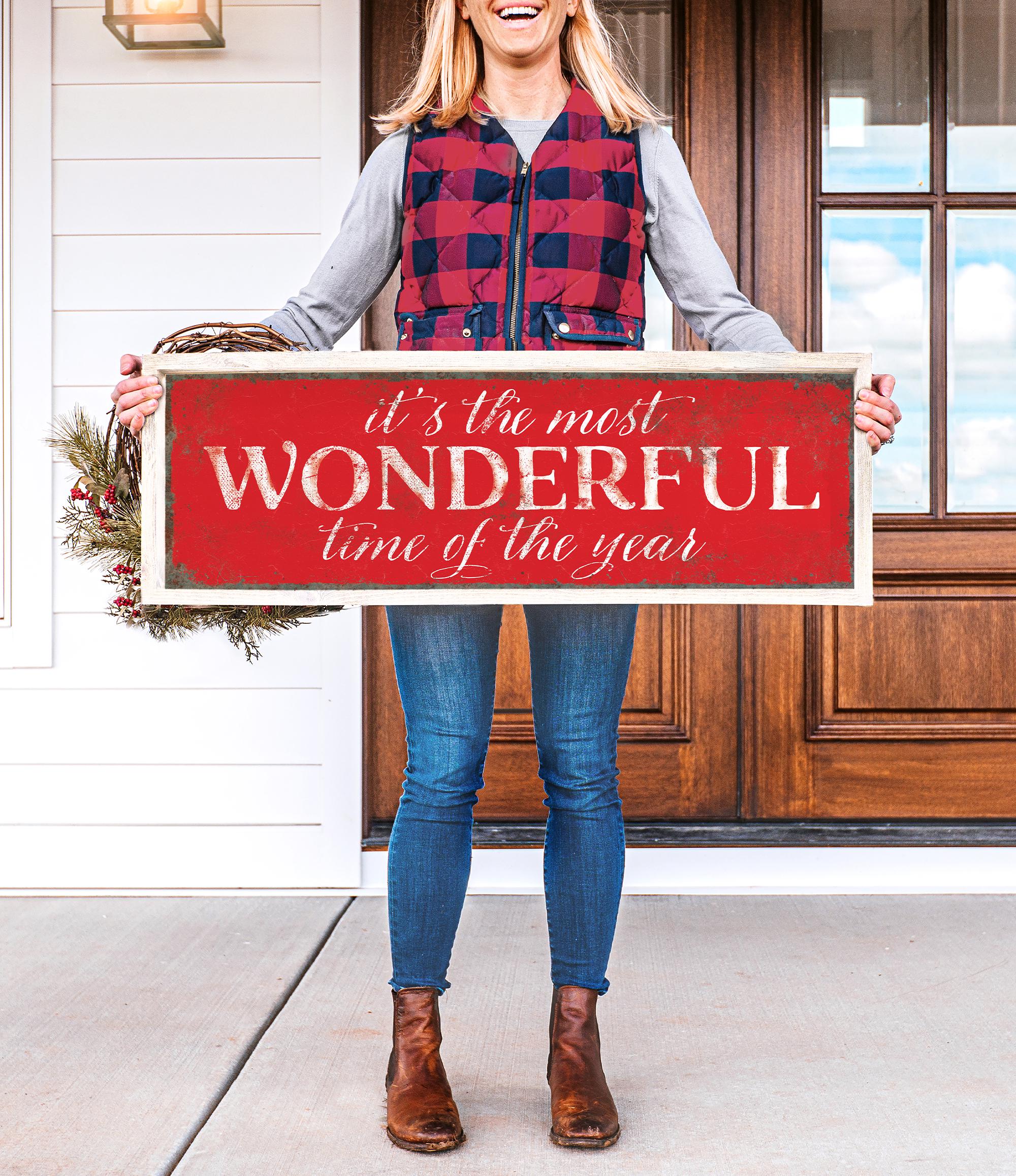 a woman holding a sign that says it&#39;s the most wonderful time of the