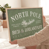 a woman holding a sign that says north pole bed and breakfast