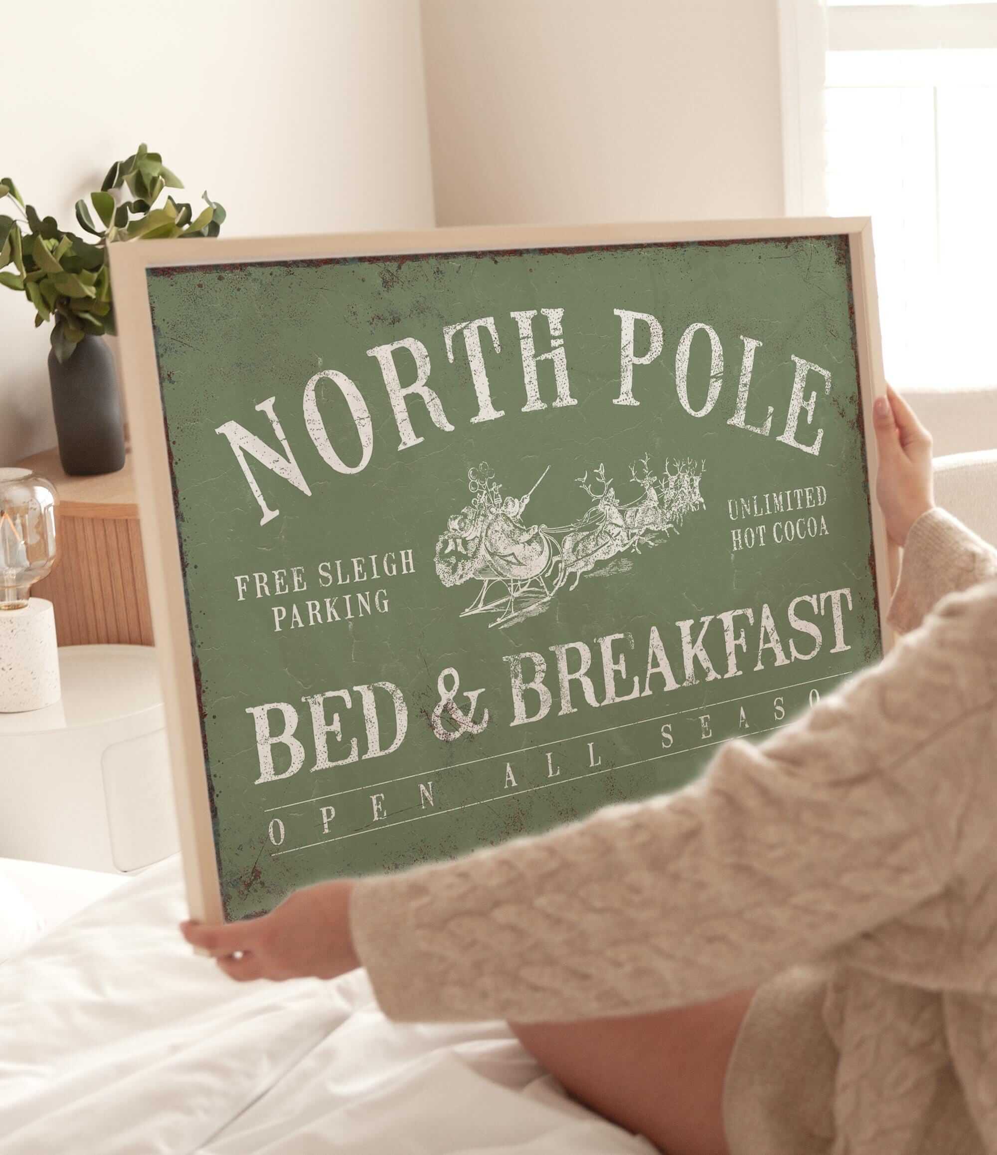 a woman holding a sign that says north pole bed and breakfast