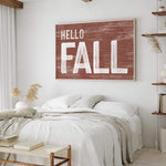 a bedroom with a white bed and a hello fall sign on the wall