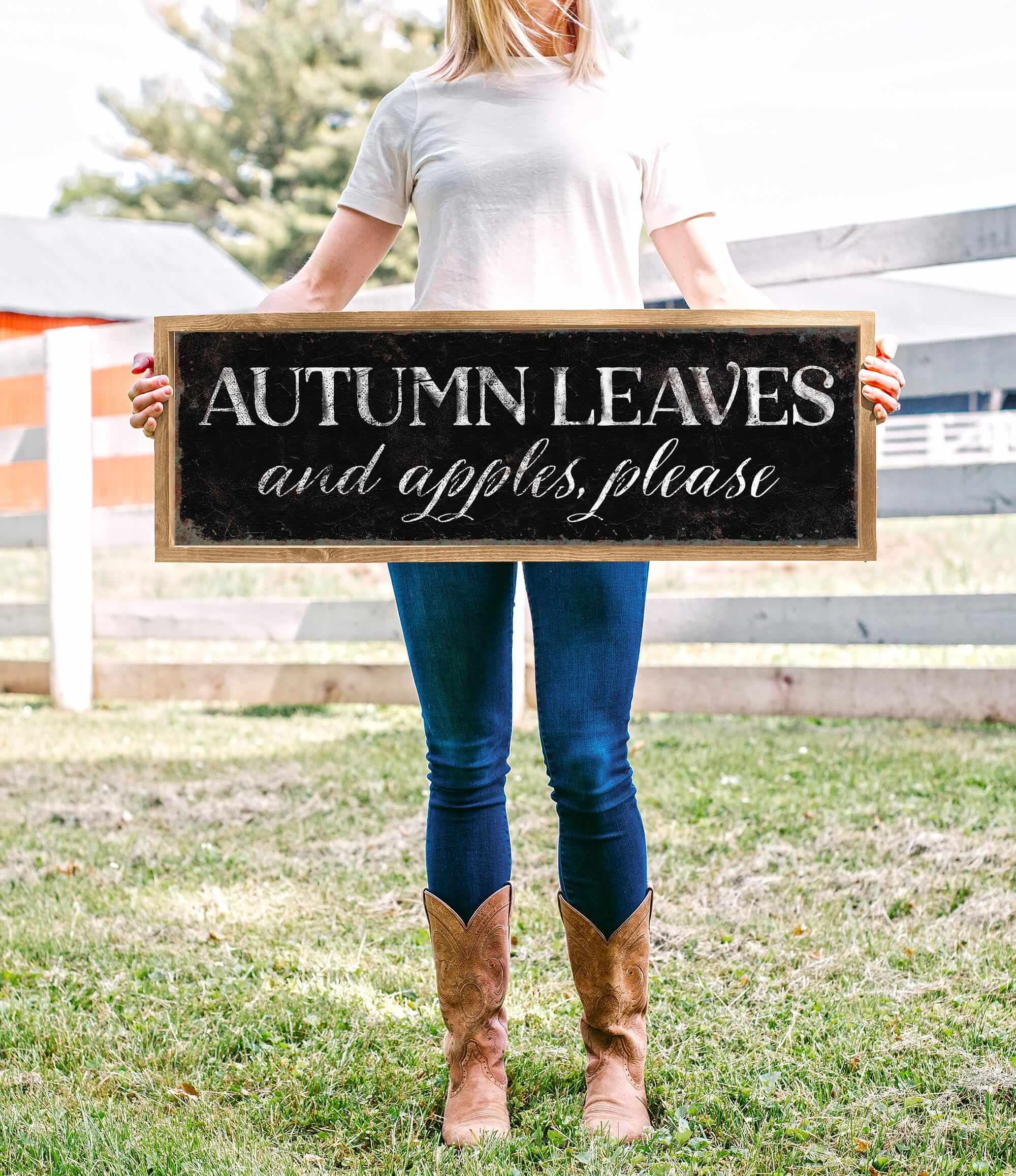 a woman holding a sign that says autumn leaves and apples please