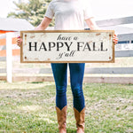 a woman holding a sign that says have a happy fall y'all