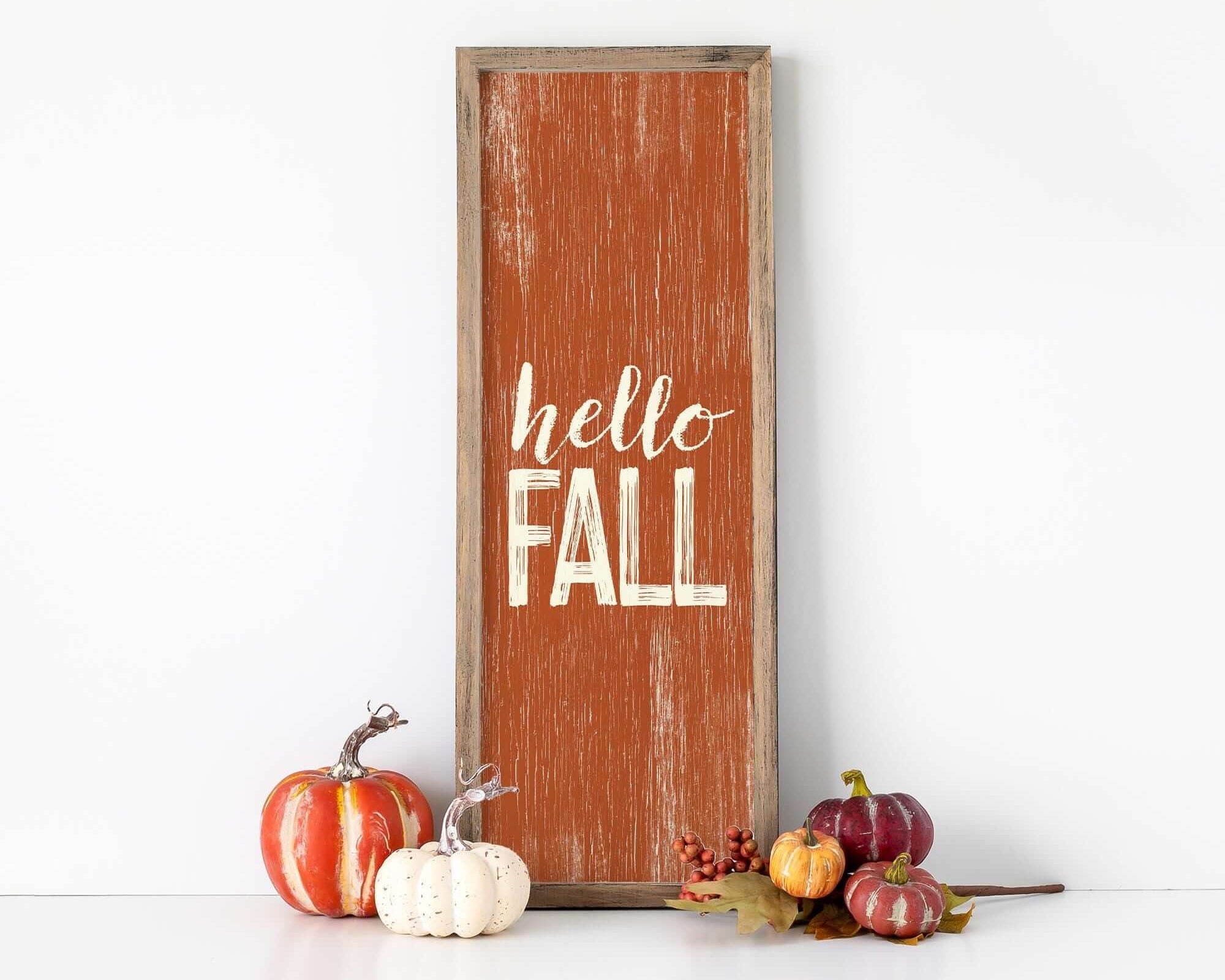 a wooden sign that says hello fall next to some pumpkins