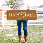 a woman holding a sign that says have a happy fall y'all