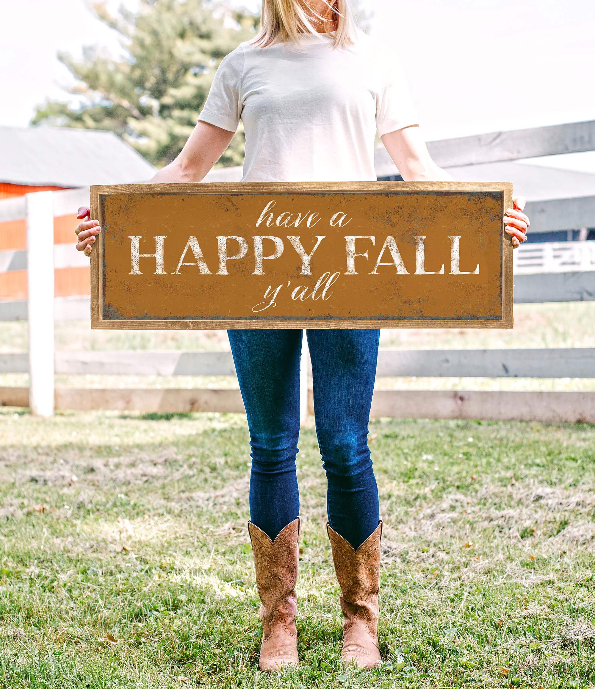 a woman holding a sign that says have a happy fall y'all