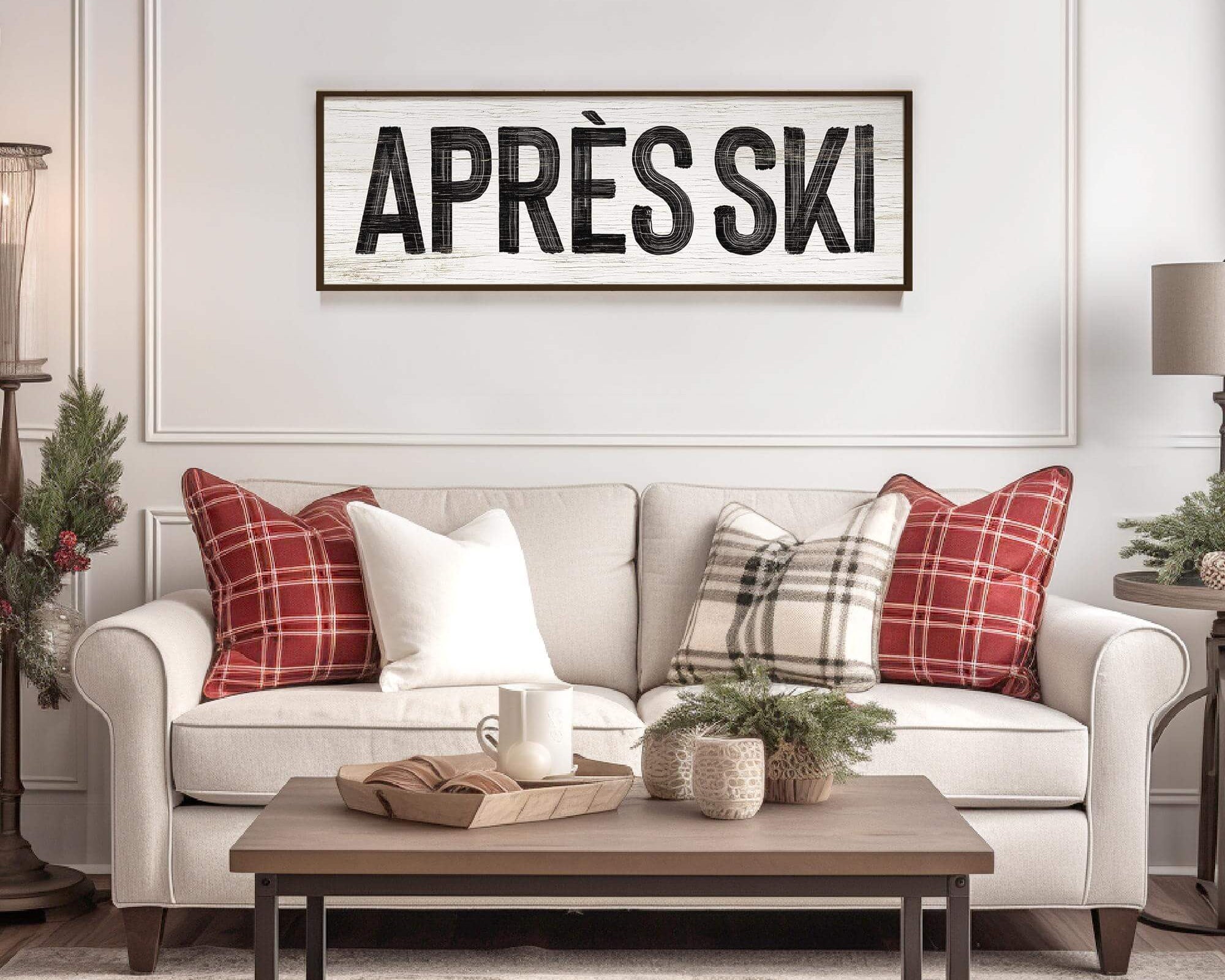 A cozy living room with a beige sofa, plaid pillows, Christmas accents, and modern farmhouse style, featuring a winter "Apres Ski Sign, White" on the wall.