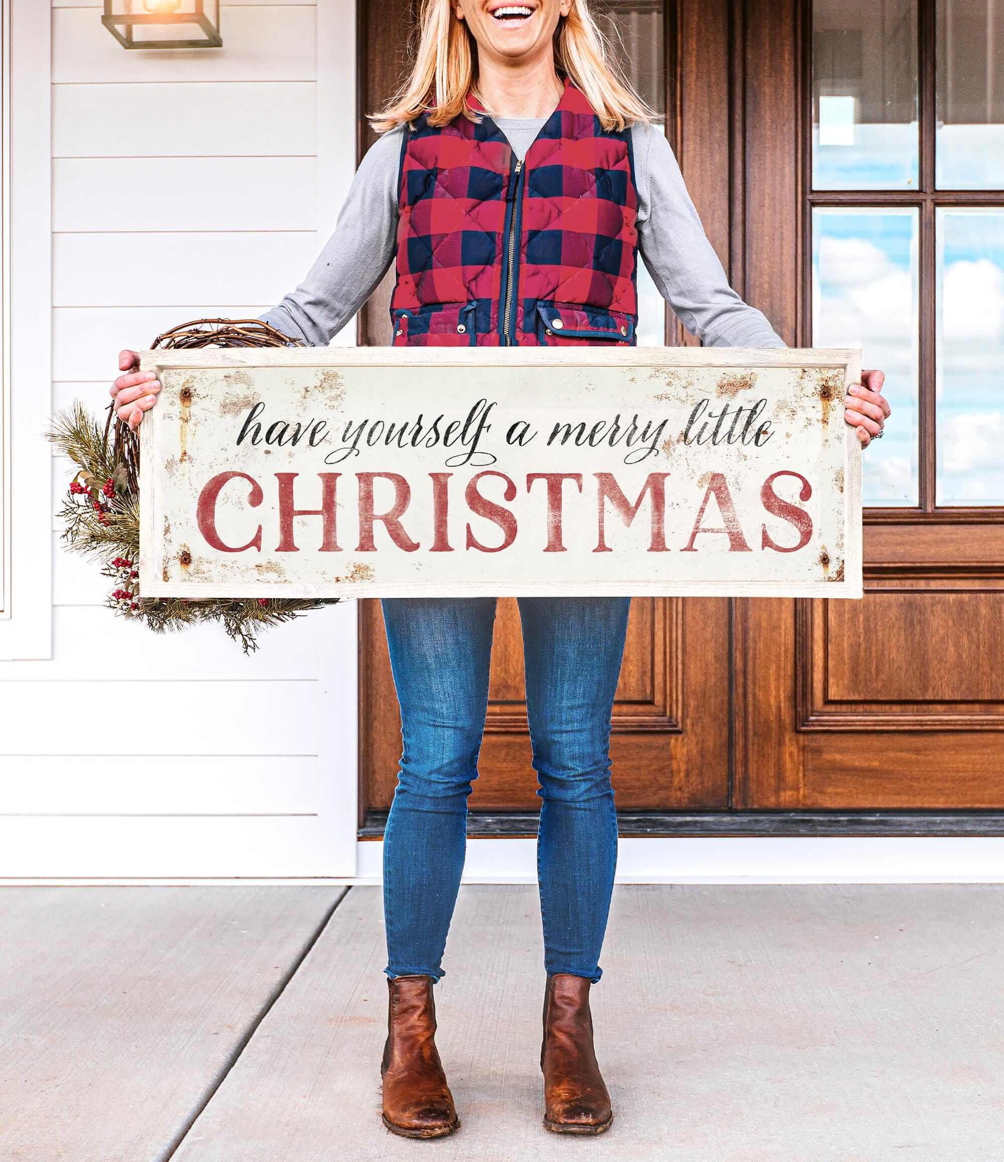 a woman holding a sign that says have yourself a merry little christmas