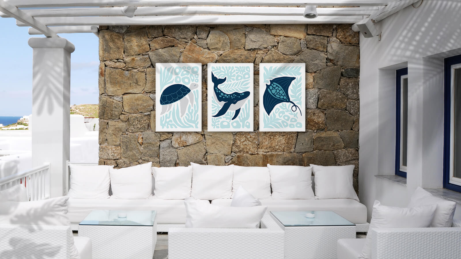 Outdoor patio with white furniture, stone wall, and three blue marine animal artworks displayed above the seating.